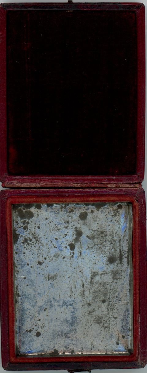 Case. Open daguerreotype case with black fabric in the top is lined with mottled silvery tin in the bottom.